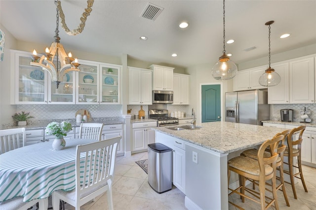 11044 Spring Point Cir, Riverview, FL 33579 - kitchen featuring stainless steel appliances, tasteful backsplash, an island with sink, glass insert cabinets, and white cabinets