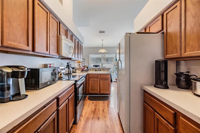 7046 Frascati Loop, Wesley Chapel, FL 33544 - kitchen featuring white appliances, light wood-style flooring, brown cabinets, light countertops, and decorative light fixtures