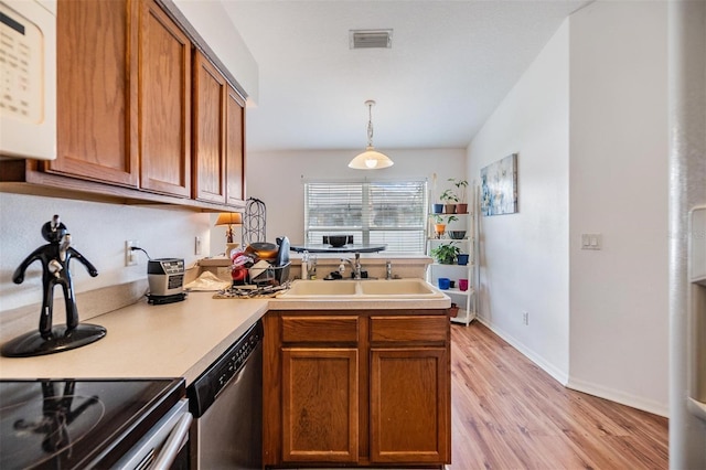 7046 Frascati Loop, Wesley Chapel, FL 33544 - kitchen featuring stainless steel appliances, a peninsula, light wood finished floors, brown cabinetry, and light countertops
