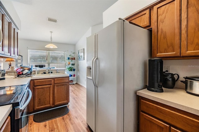 7046 Frascati Loop, Wesley Chapel, FL 33544 - kitchen with white fridge with ice dispenser, electric range, brown cabinets, and vaulted ceiling