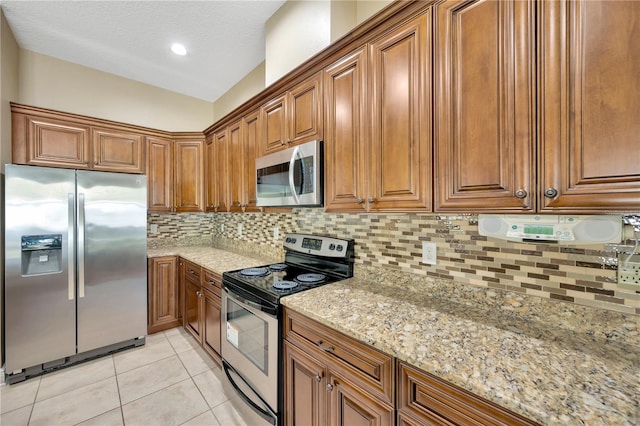 320 Roxbury Crossing Ct, Valrico, FL 33594 - kitchen with appliances with stainless steel finishes, brown cabinets, tasteful backsplash, light stone counters, and a textured ceiling