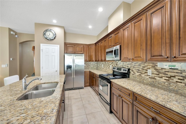 320 Roxbury Crossing Ct, Valrico, FL 33594 - kitchen featuring stainless steel appliances, arched walkways, decorative backsplash, light stone counters, and light tile patterned floors
