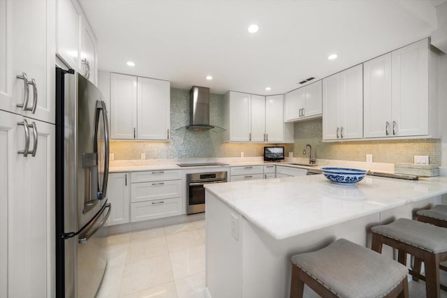 4 Belleview Blvd Unit 305, Belleair, FL 33756 - kitchen with appliances with stainless steel finishes, wall chimney range hood, a peninsula, a breakfast bar area, and white cabinetry