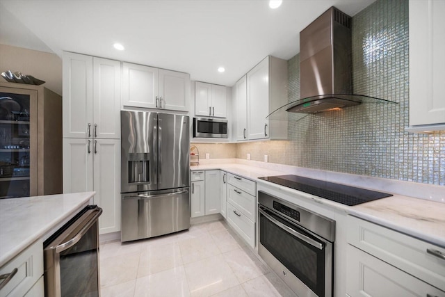 4 Belleview Blvd Unit 305, Belleair, FL 33756 - kitchen featuring appliances with stainless steel finishes, wall chimney range hood, light tile patterned floors, white cabinetry, and tasteful backsplash