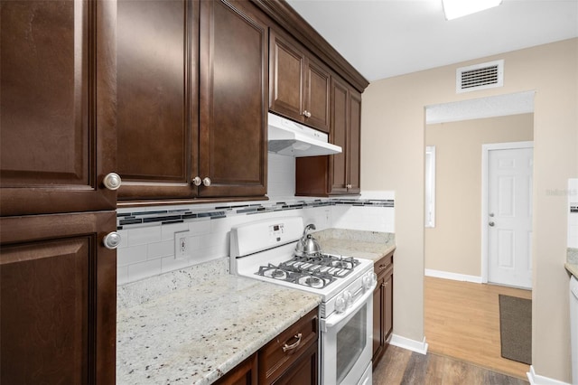 10033 64th Ave N Unit 4, Saint Petersburg, FL 33708 - kitchen featuring white gas range, dark wood-style flooring, under cabinet range hood, dark brown cabinets, and tasteful backsplash