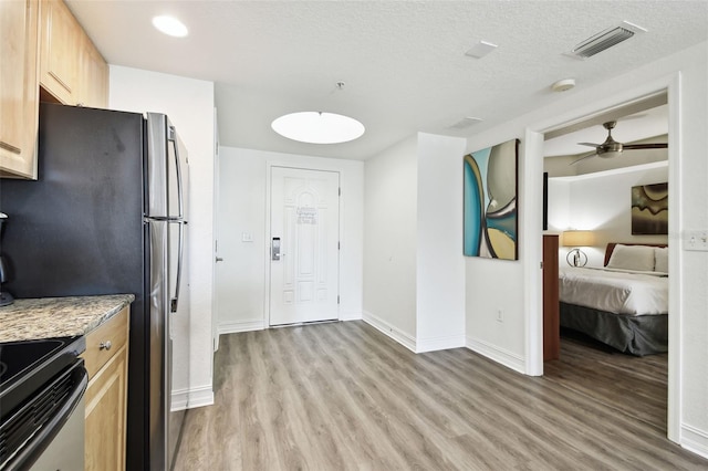 11605 Gulf Blvd Unit 402, Saint Petersburg, FL 33706 - kitchen featuring light wood-style flooring, appliances with stainless steel finishes, light brown cabinetry, ceiling fan, and a textured ceiling