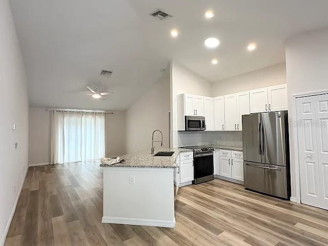 1737 N Lakewood Ave, Ocoee, FL 34761 - kitchen with stainless steel appliances, lofted ceiling, light stone counters, light wood-style flooring, and a peninsula