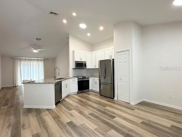 1737 N Lakewood Ave, Ocoee, FL 34761 - kitchen with appliances with stainless steel finishes, a peninsula, light stone counters, light wood-style floors, and white cabinetry