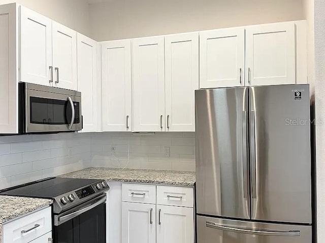 1737 N Lakewood Ave, Ocoee, FL 34761 - kitchen with stainless steel appliances, decorative backsplash, white cabinetry, and light stone countertops
