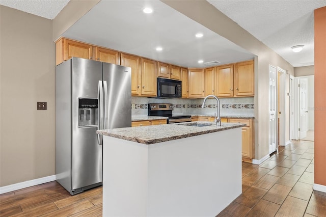 7112 2nd St N, Saint Petersburg, FL 33702 - kitchen with appliances with stainless steel finishes, wood finished floors, tasteful backsplash, light stone counters, and an island with sink