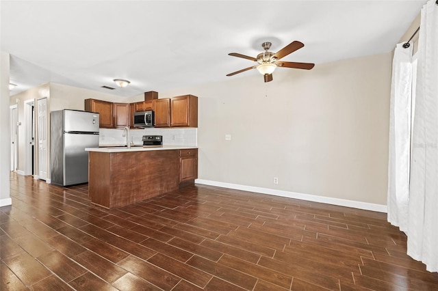 7112 2nd St N, Saint Petersburg, FL 33702 - kitchen with stainless steel appliances, dark wood-type flooring, ceiling fan, brown cabinets, and a peninsula