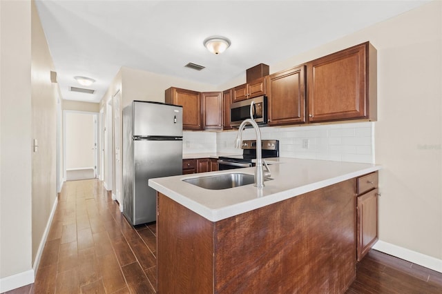 7112 2nd St N, Saint Petersburg, FL 33702 - kitchen with stainless steel appliances, dark wood-style floors, decorative backsplash, a peninsula, and light countertops