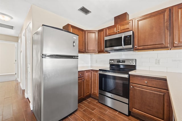 7112 2nd St N, Saint Petersburg, FL 33702 - kitchen featuring stainless steel appliances, dark wood-style flooring, light countertops, and decorative backsplash