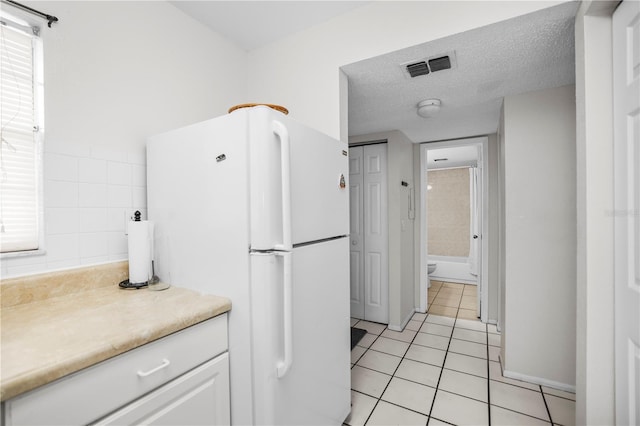 2625 State Road 590 Unit 723, Clearwater, FL 33759 - kitchen featuring freestanding refrigerator, light tile patterned floors, white cabinets, light countertops, and a textured ceiling
