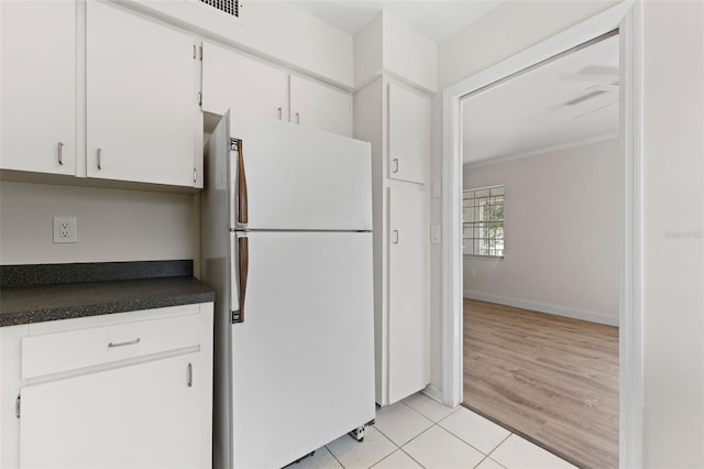 4313 W N A St, Tampa, FL 33609 - kitchen with freestanding refrigerator, dark countertops, white cabinetry, light tile patterned flooring, and ornamental molding