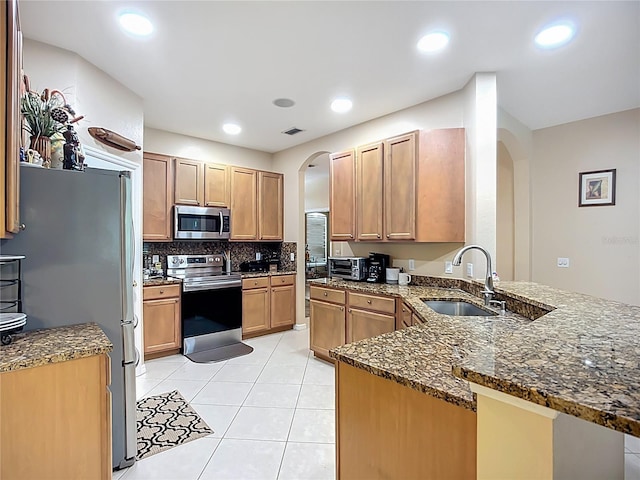 3409 61st Ter E, Ellenton, FL 34222 - kitchen with stainless steel appliances, arched walkways, a peninsula, dark stone counters, and decorative backsplash