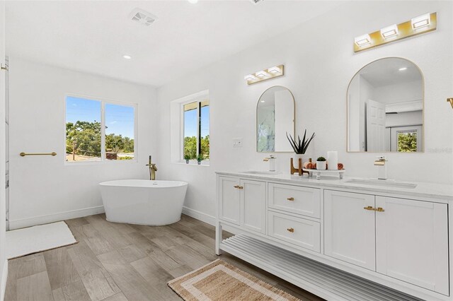 380 Colony Point Rd S, Saint Petersburg, FL 33705 - full bath featuring double vanity, a freestanding bath, wood finished floors, and recessed lighting