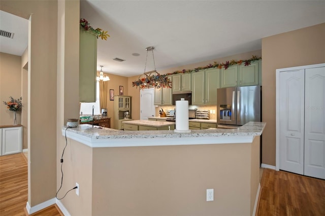 8607 Tidal Breeze Dr, Riverview, FL 33569 - kitchen with stainless steel fridge, light wood-style flooring, a peninsula, light stone countertops, and a chandelier