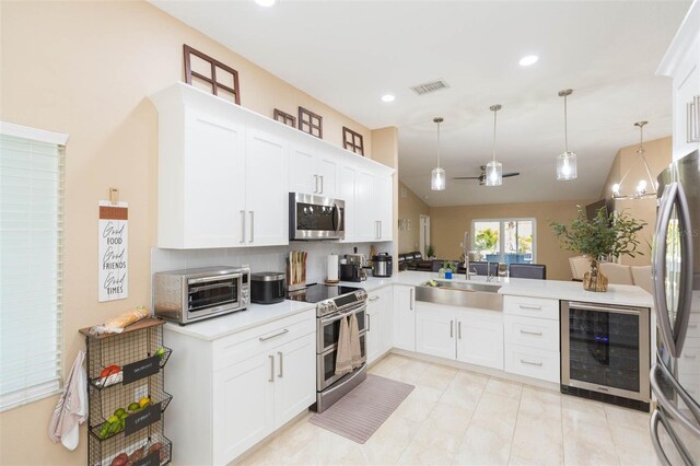 11913 Butler Woods Cir, Riverview, FL 33579 - kitchen with appliances with stainless steel finishes, beverage cooler, light countertops, tasteful backsplash, and pendant lighting