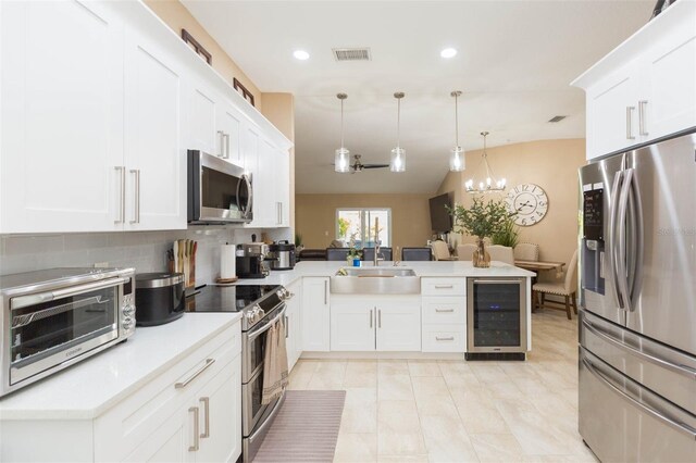 11913 Butler Woods Cir, Riverview, FL 33579 - kitchen featuring appliances with stainless steel finishes, beverage cooler, a peninsula, white cabinets, and recessed lighting