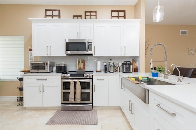 11913 Butler Woods Cir, Riverview, FL 33579 - kitchen featuring stainless steel appliances, light countertops, tasteful backsplash, white cabinetry, and hanging light fixtures