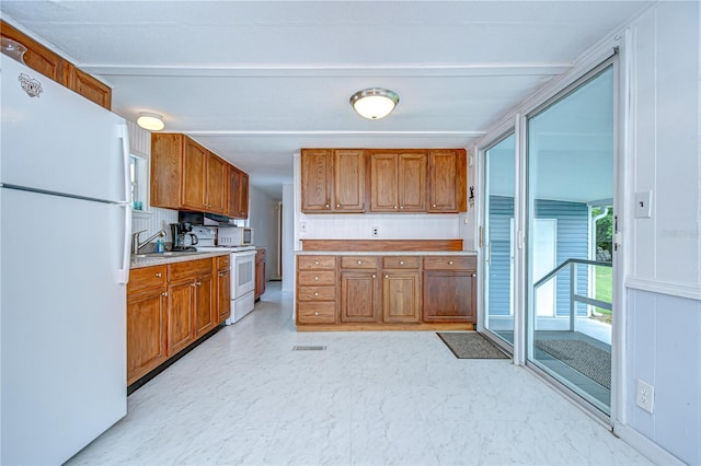 35014 Carl Ave, Zephyrhills, FL 33541 - kitchen featuring white appliances, light countertops, and brown cabinetry