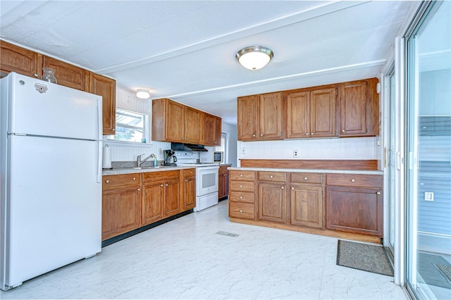 35014 Carl Ave, Zephyrhills, FL 33541 - kitchen featuring white appliances, light countertops, brown cabinets, and light flooring