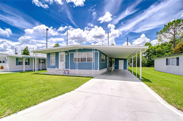 35014 Carl Ave, Zephyrhills, FL 33541 - manufactured / mobile home with entry steps, driveway, a front lawn, and an attached carport