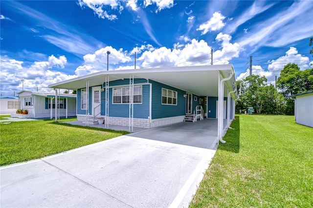 35014 Carl Ave, Zephyrhills, FL 33541 - manufactured / mobile home featuring entry steps, concrete driveway, a front lawn, and a carport