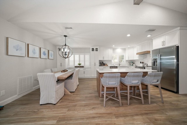 11763 Saree Ct, Largo, FL 33778 - kitchen featuring stainless steel refrigerator with ice dispenser, a chandelier, white cabinetry, a kitchen breakfast bar, and light countertops