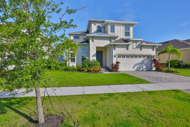 955 Signet Dr, Apollo Beach, FL 33572 - view of front of home featuring stucco siding, decorative driveway, a front lawn, and board and batten siding