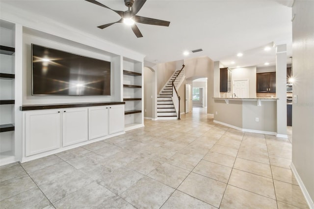 3530 Brook Crossing Dr, Brandon, FL 33511 - unfurnished living room featuring ceiling fan, light tile patterned floors, stairway, built in shelves, and arched walkways