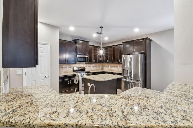 3530 Brook Crossing Dr, Brandon, FL 33511 - kitchen featuring appliances with stainless steel finishes, light stone counters, dark brown cabinetry, decorative backsplash, and pendant lighting