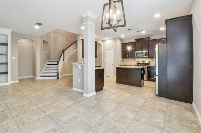 3530 Brook Crossing Dr, Brandon, FL 33511 - kitchen featuring appliances with stainless steel finishes, arched walkways, dark brown cabinetry, a kitchen island, and tasteful backsplash