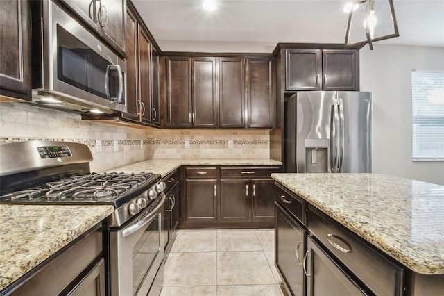 3530 Brook Crossing Dr, Brandon, FL 33511 - kitchen featuring appliances with stainless steel finishes, light stone counters, dark brown cabinetry, decorative backsplash, and light tile patterned floors