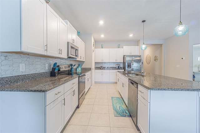 13527 Willow Bluestar Loop, Riverview, FL 33579 - kitchen with appliances with stainless steel finishes, tasteful backsplash, light tile patterned flooring, white cabinetry, and an island with sink