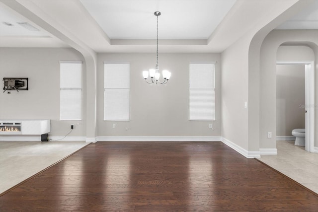 3994 Medicci Ln, Wesley Chapel, FL 33543 - spare room with arched walkways, a tray ceiling, wood finished floors, a chandelier, and plenty of natural light