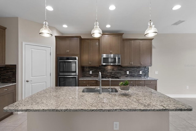 3994 Medicci Ln, Wesley Chapel, FL 33543 - kitchen featuring appliances with stainless steel finishes, light tile patterned flooring, tasteful backsplash, a kitchen island with sink, and recessed lighting