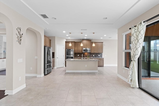 3994 Medicci Ln, Wesley Chapel, FL 33543 - kitchen featuring appliances with stainless steel finishes, backsplash, light tile patterned floors, a kitchen island with sink, and arched walkways