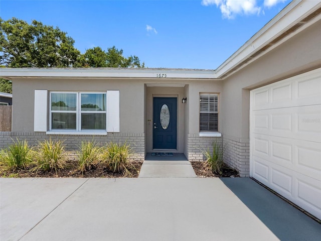 1675 E Grovehill Rd, Palm Harbor, FL 34683 - view of exterior entry featuring brick siding, a garage, and stucco siding