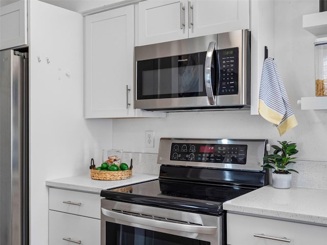 1675 E Grovehill Rd, Palm Harbor, FL 34683 - kitchen featuring appliances with stainless steel finishes, white cabinetry, and light stone counters