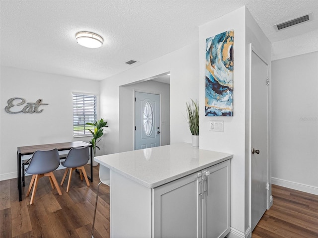 1675 E Grovehill Rd, Palm Harbor, FL 34683 - kitchen with a textured ceiling, dark wood-style flooring, a breakfast bar area, light stone counters, and a desk