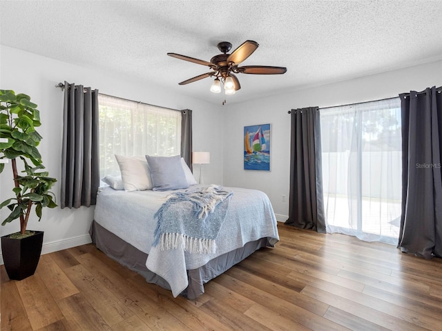 1675 E Grovehill Rd, Palm Harbor, FL 34683 - bedroom featuring wood finished floors, a textured ceiling, a ceiling fan, and access to exterior