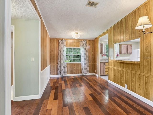 26223 Chianina Dr, Wesley Chapel, FL 33544 - kitchen with freestanding refrigerator, wood-type flooring, a textured ceiling, wood walls, and brown cabinets