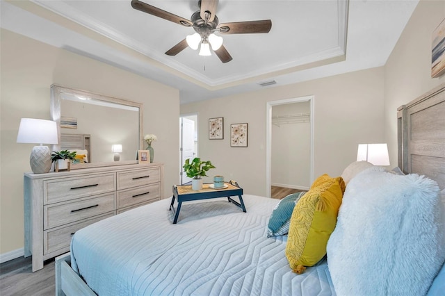 1561 S Martin Luther King Jr Ave, Clearwater, FL 33756 - bedroom featuring a raised ceiling, light wood-style floors, a ceiling fan, ornamental molding, and a walk in closet