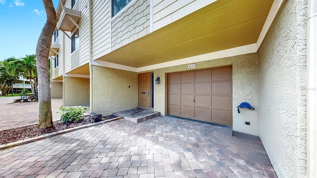 459 Haven Point Dr, Treasure Island, FL 33706 - view of exterior entry with an attached garage, stucco siding, and decorative driveway