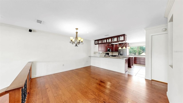 459 Haven Point Dr, Treasure Island, FL 33706 - kitchen with a chandelier, a peninsula, light wood-style flooring, pendant lighting, and light countertops