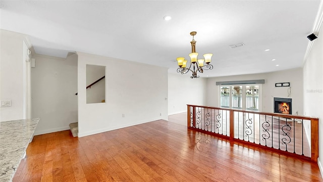 459 Haven Point Dr, Treasure Island, FL 33706 - spare room with a chandelier, wood-type flooring, a warm lit fireplace, and recessed lighting