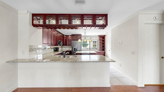 459 Haven Point Dr, Treasure Island, FL 33706 - kitchen featuring appliances with stainless steel finishes, reddish brown cabinets, a peninsula, tasteful backsplash, and light stone counters