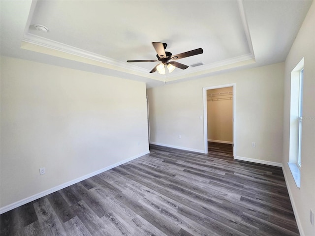 1557 S Martin Luther King Jr Ave, Clearwater, FL 33756 - unfurnished bedroom with a raised ceiling, ornamental molding, dark wood-style floors, a walk in closet, and a closet